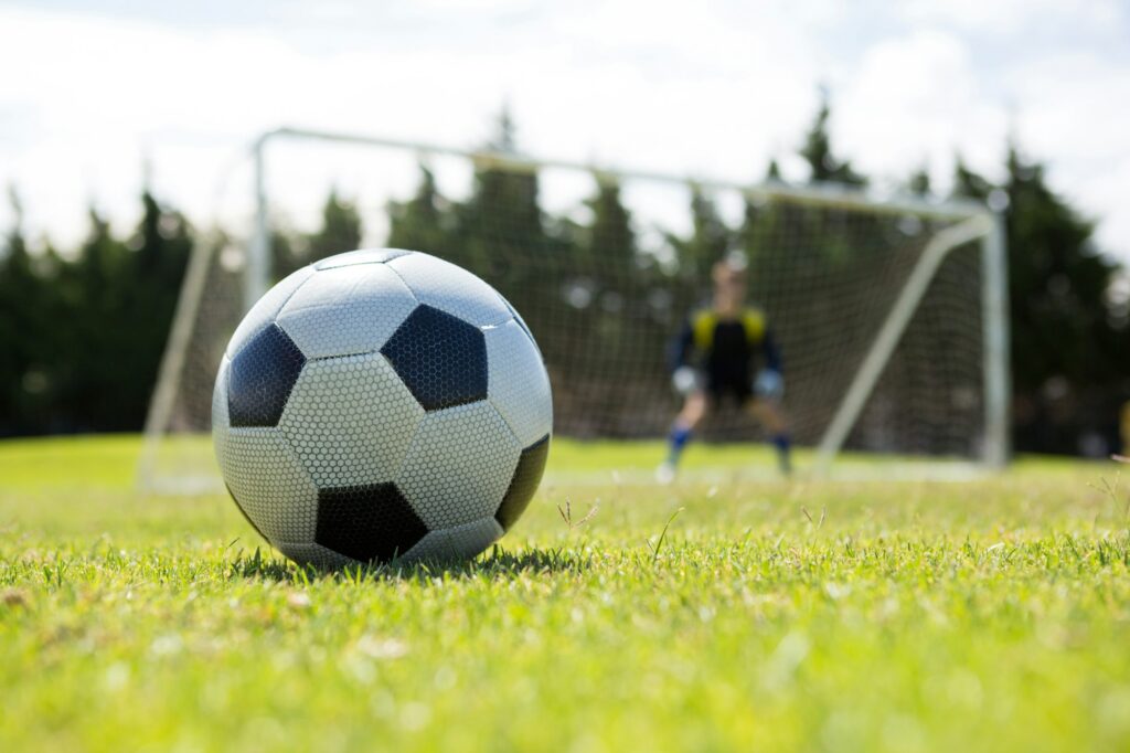 Soccer ball on field against goalkeeper