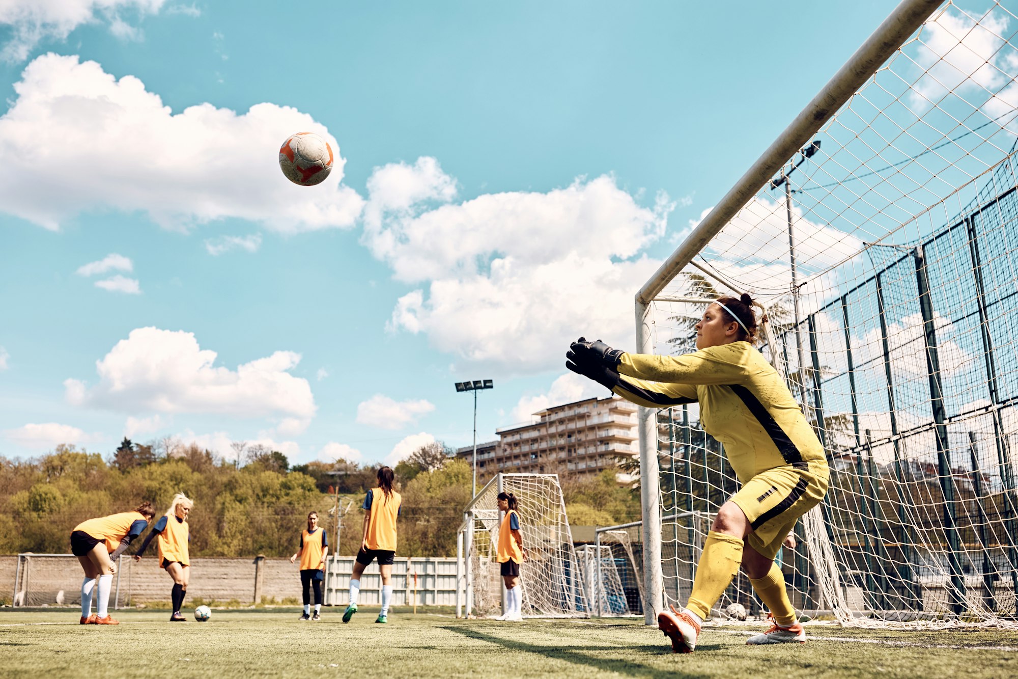 Soccer goalie catching the ball while having sports training on playing field.